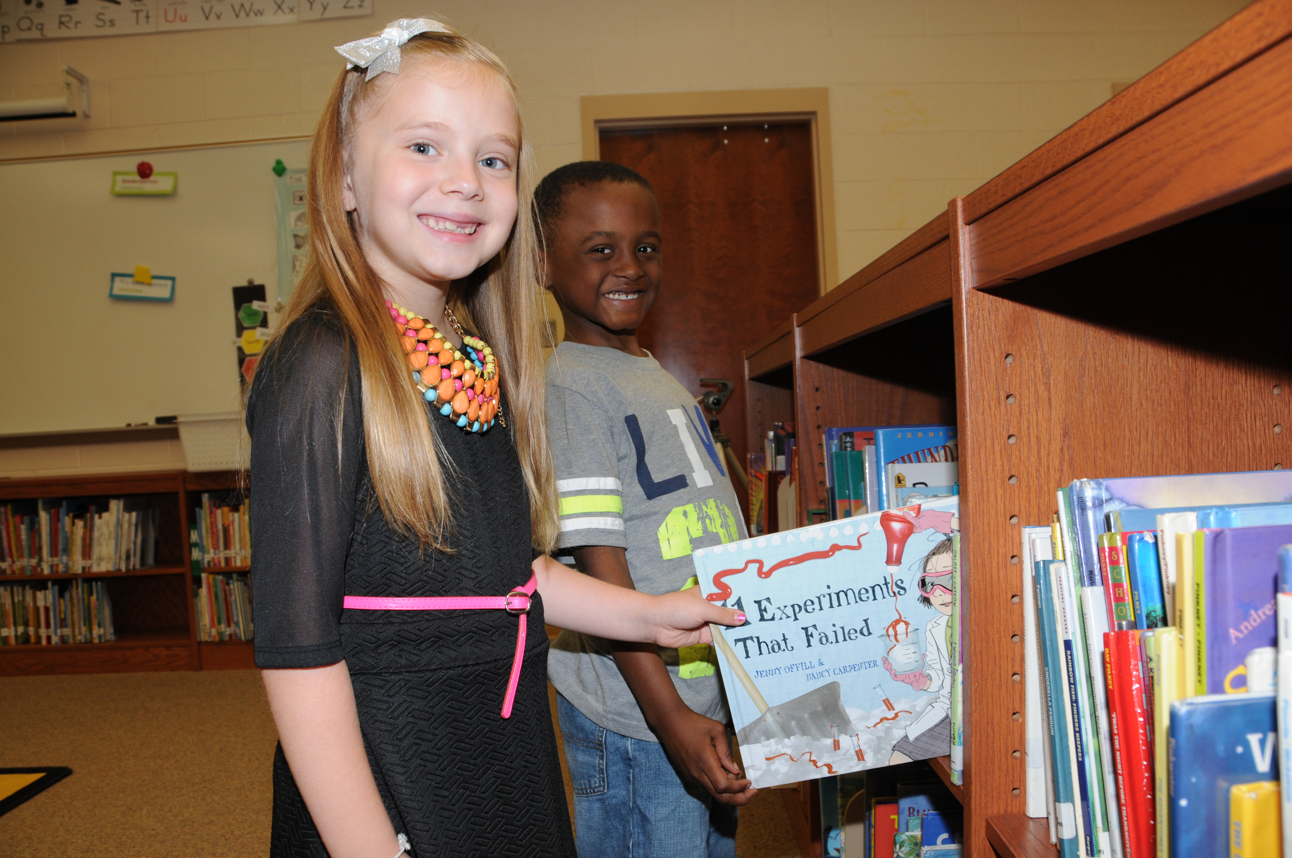 Two elementary school students choosing a book from the media center.