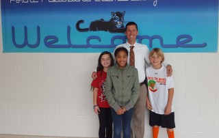 Principal Christopher Gordon standing with three students