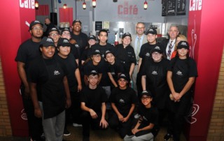 A large group of students stand in their employee uniforms at the Cafe at Maryland Hall