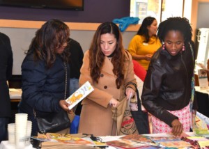 Three female parents gather books and other materials during the Resource Fair.