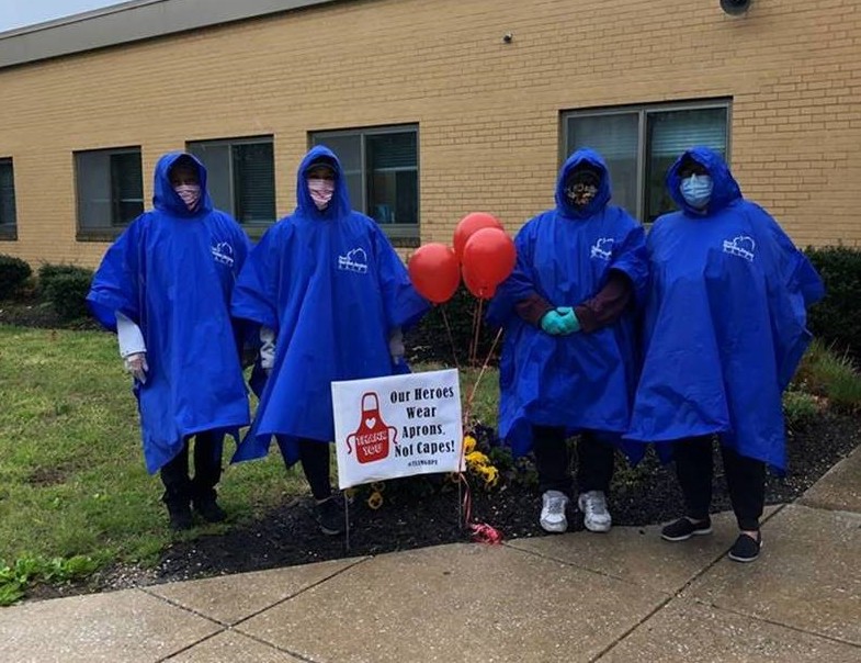 A group of four cafeteria staff members in rain gear standing outside of Glen Burnie Park Elementary