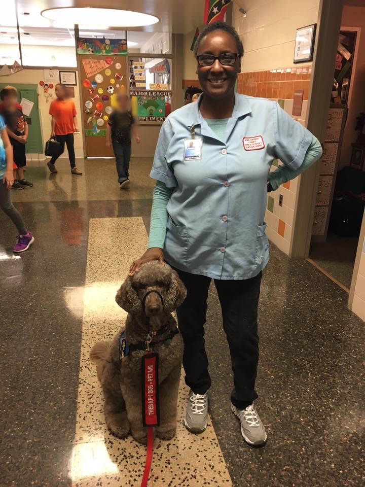 Sarah Moulden, the custodian at Southgate Elementary, standing with a service dog.