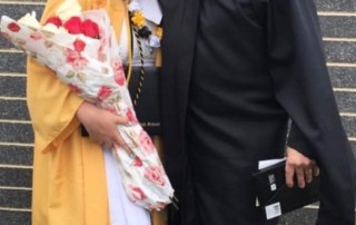 Photograph of Mackenzie Jones in her graduation robes standing next to Danny Imwold