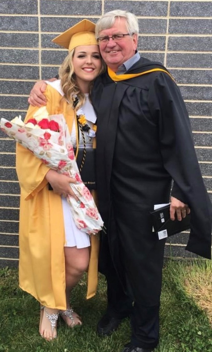 Photograph of Mackenzie Jones in her graduation robes standing next to Danny Imwold