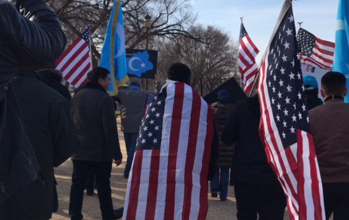 People marching with American and East Turkistan flags