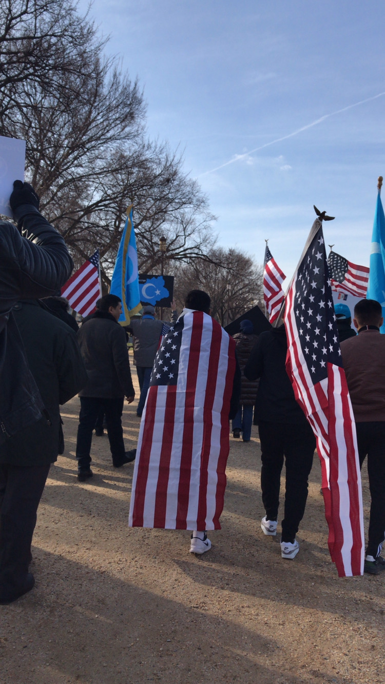 People marching with American and East Turkistan flags